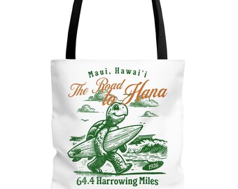 May include: White tote bag with a green turtle carrying a surfboard. The bag has the text "Maui, Hawai'i The Road to Hana 64.4 Harrowing Miles" printed on it.