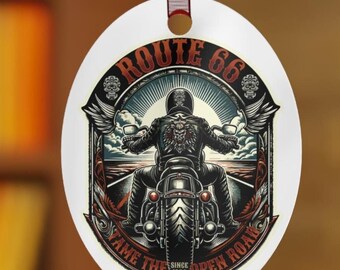 Op de afbeelding: Een witte ovale kerstbal met een zwart-witte illustratie van een motorrijder op Route 66. De tekst "Route 66" staat in een rode cirkel met een zwarte rand. De tekst "Tame the Open Road" staat in een rode banner onder de motorfiets. De tekst "Since 1926" staat in een kleine witte banner onder de motorfiets.