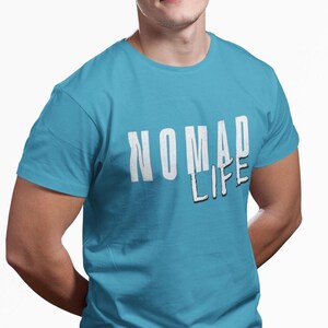May include: A turquoise t-shirt with the words "NOMAD LIFE" printed in white, with a black shadow effect. The shirt has short sleeves and a crew neck.