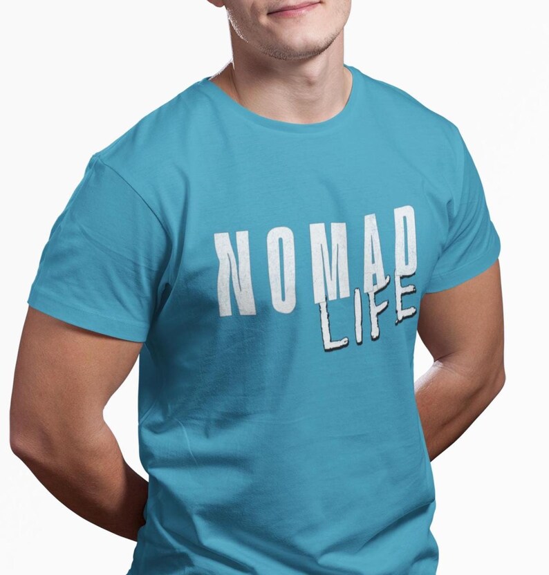 May include: A turquoise t-shirt with the words "NOMAD LIFE" printed in white, with a black shadow effect. The shirt has short sleeves and a crew neck.
