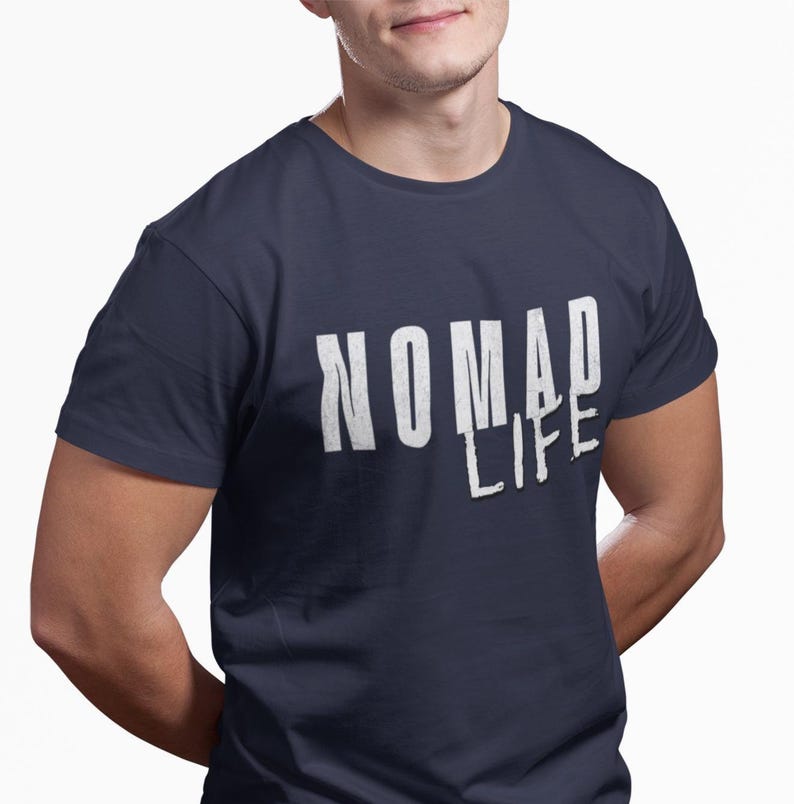 May include: Navy blue t-shirt with the white text "NOMAD LIFE". The text has a distressed, textured appearance. The shirt is a crew neck style and appears to be made of a soft material.