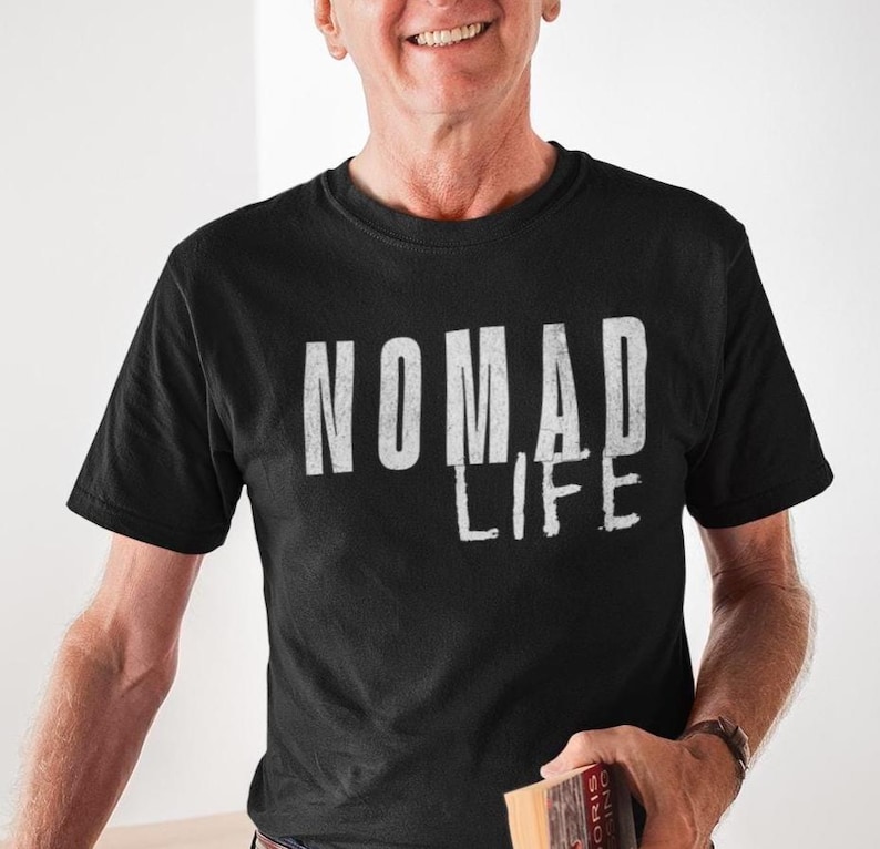 May include: Black crew neck t-shirt with the white text "NOMAD LIFE". The shirt is made of a soft material. The shirt is a casual wear item.