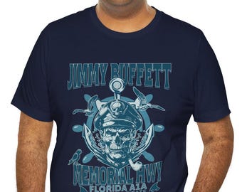 Könnte beinhalten: Ein marineblaues T-Shirt mit einem Grafikdruck eines Schädels, der einen Kapitänshut trägt und eine Pfeife hält. Der Text "Jimmy Buffett Memorial Hwy Florida A1A Yes, I am a pirate" ist auf dem T-Shirt aufgedruckt.