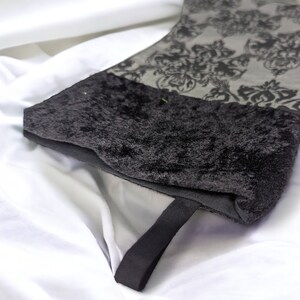 May include: A black velvet stocking with a black satin ribbon and a gray and black damask pattern.