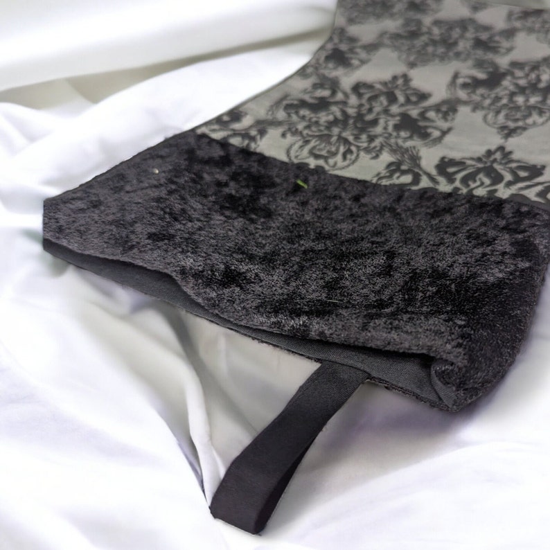May include: A black velvet stocking with a black satin ribbon and a gray and black damask pattern.