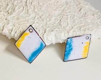 May include: A pair of diamond-shaped earrings. Each earring has a white base with yellow and blue paint accents. The edges are dark brown, and there's a small hole at the top for hanging. The earrings are approximately 2.5 cm in length.