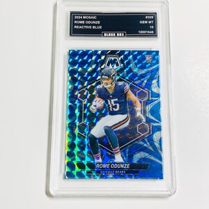 Pu&ograve; includere: Una carta collezionabile di football Mosaic 2024 con Rome Odunze dei Chicago Bears. La carta ha un design blu reattivo ed &egrave; classificata GEM MT 10. La carta &egrave; racchiusa in un supporto protettivo.