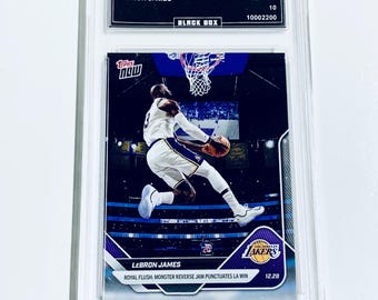 Op de afbeelding: Een LeBron James basketbalkaart in een beschermhoes. De kaart is van de "2025 Topps Now" serie en toont James tijdens een dunk. De tekst op de kaart luidt "Royal Flush: Monster Reverse Jam Punctuate LA Win."