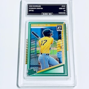 Puede incluir: Una tarjeta de b&eacute;isbol en un estuche protector transparente. La tarjeta muestra a un jugador de b&eacute;isbol con una camiseta amarilla con el n&uacute;mero 17. El texto en la tarjeta incluye "KONNOR GRIFFIN" y "OPTIC". El estuche tiene texto que dice "2025 DONRUSS" y "BLACK BOX".