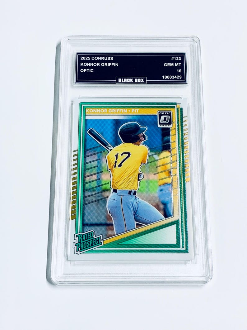 Puede incluir: Una tarjeta de b&eacute;isbol en un estuche protector transparente. La tarjeta muestra a un jugador de b&eacute;isbol con una camiseta amarilla con el n&uacute;mero 17. El texto en la tarjeta incluye "KONNOR GRIFFIN" y "OPTIC". El estuche tiene texto que dice "2025 DONRUSS" y "BLACK BOX".