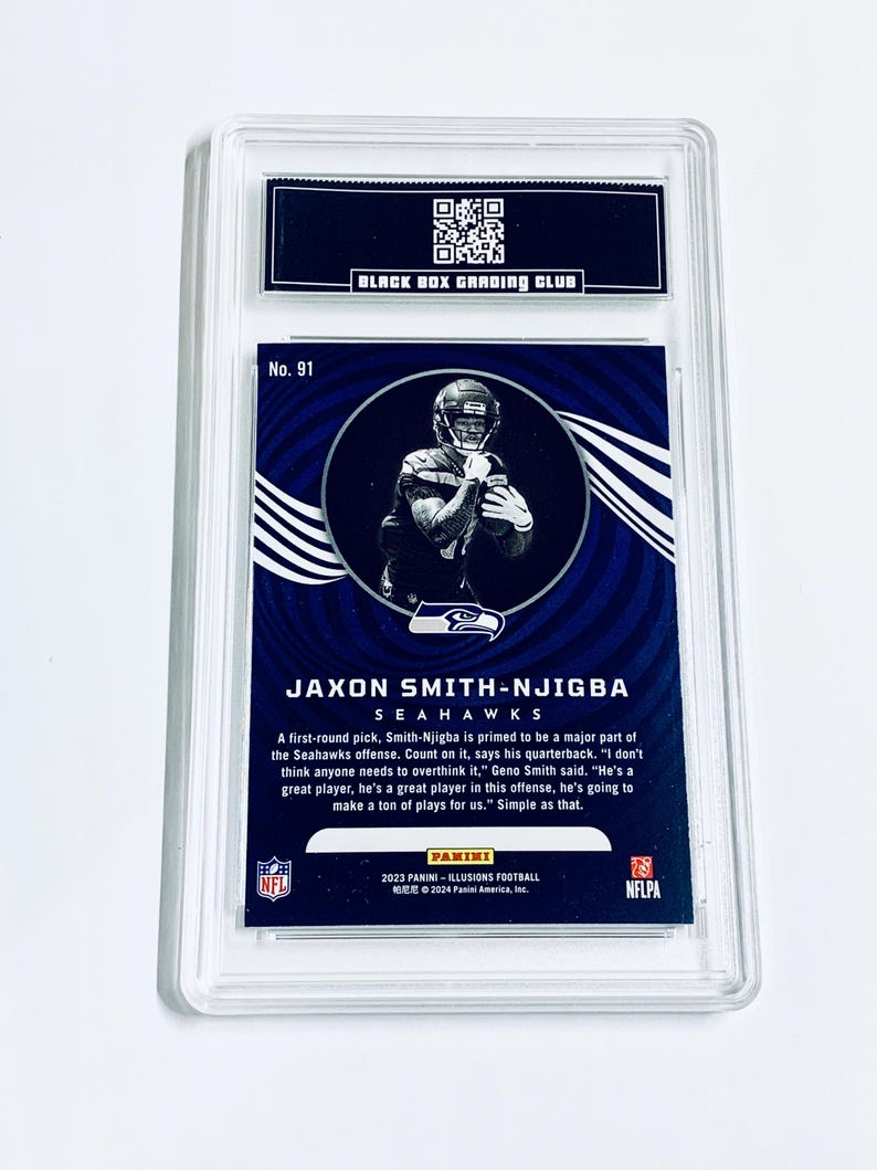 May include: A Jaxon Smith-Njigba Seahawks football card, graded by Black Box Grading Club, encased in a clear protective holder. The card features a player image and text, including "2023 Panini - Illusions Football."