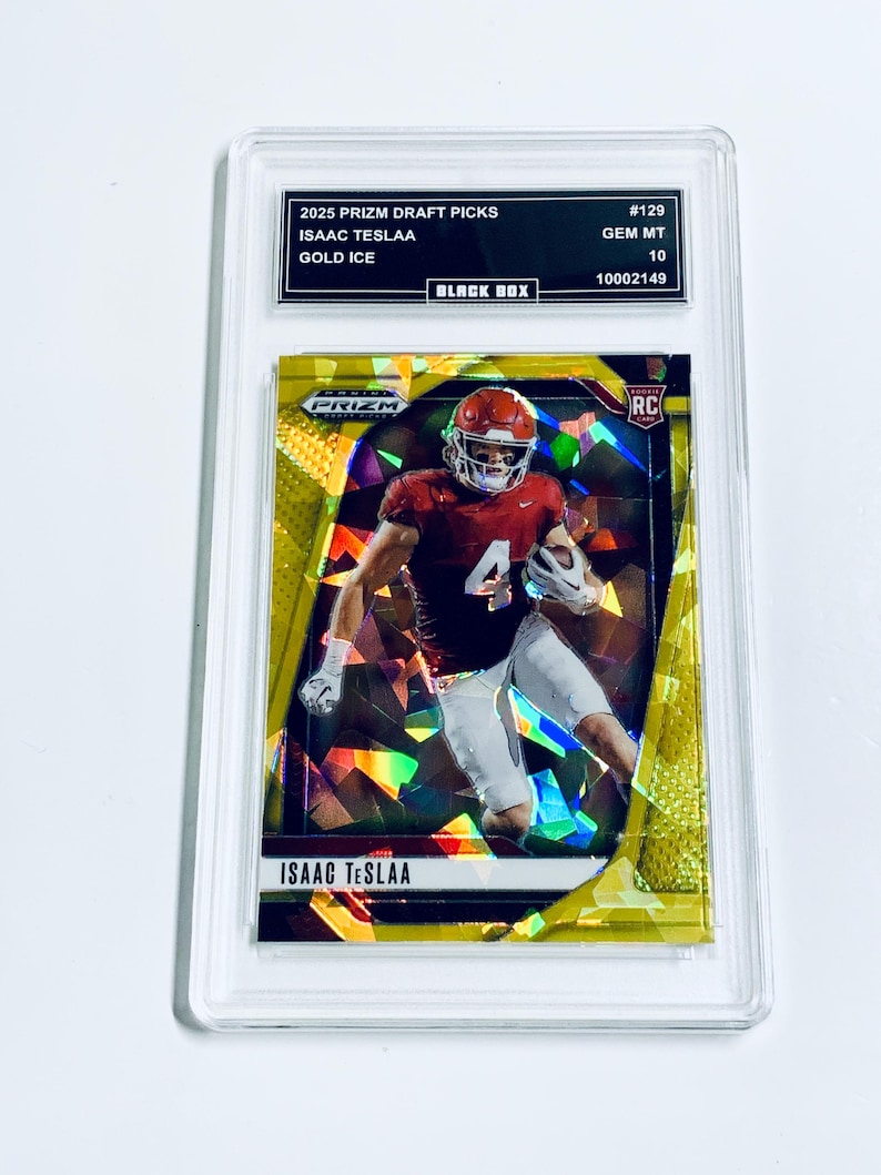 K&ouml;nnte beinhalten: Eine goldfarbene Sport-Sammelkarte mit Isaac Teslaa in Football-Uniform, in einer transparenten Schutzh&uuml;lle. Der Text enth&auml;lt "2025 Prizm Draft Picks", "Gold Ice" und "RC".