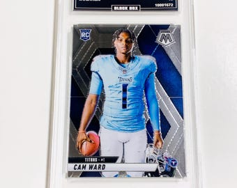 May include: A Cam Ward football trading card from the 2025 Mosaic series, encased in a protective holder. The card features a player in a light blue uniform, holding a football. The card's details include "2025 MOSAIC", "CAM WARD", and "TITANS - #1".
