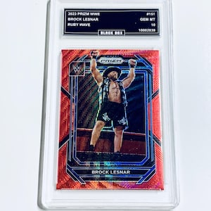 Op de afbeelding: 2023 Prizm WWE verzamelkaart met Brock Lesnar in Ruby Wave design, in een beschermhoes. De kaart heeft de tekst "BLACK BOX" en is beoordeeld met GEM MT 10. Een verzamelobject.