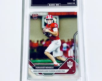 May include: A graded sports trading card featuring Fernando Mendoza in a red and white football uniform. The card is encased in a clear plastic holder with text that reads "2025 Bowman U Now" and "Black Box". The card is graded GEM MT 10.