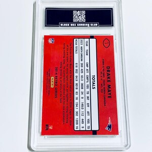 May include: A graded Drake Maye football card from the 2014 Retro Series. The card has a red background with player stats and the Patriots logo. It's encased in a clear protective holder by Black Box Grading Club.