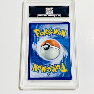 May include: A graded Pok&eacute;mon trading card encased in a clear plastic holder. The card's back features a blue background with the Pok&eacute;mon logo and a Pok&eacute; Ball design. The holder has a black label with the text "BLACK BOX GRADING CLUB".