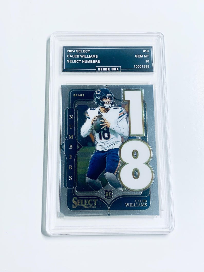 May include: A graded Caleb Williams football card from the 2024 Select series. The card features a photo of Williams in a Bears uniform, with the number 18 prominently displayed. The card is encased in a protective holder with the text "2024 SELECT" and "CALEB WILLIAMS".