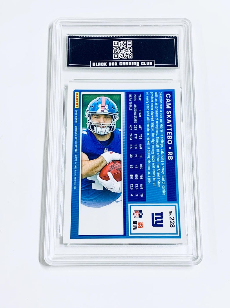 May include: A football trading card encased in a clear plastic holder. The card features a player in a blue uniform holding a football. The card's back includes player stats and the text "CAM SKATTEBO &bull; RB". The card is graded by "BLACK BOX GRADING CLUB".