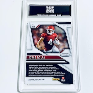 K&ouml;nnte beinhalten: Eine bewertete Sport-Sammelkarte mit einem Footballspieler in roter Uniform. Die Karte befindet sich in einem transparenten Kunststoffhalter mit dem Text "BLACK BOX GRADING CLUB" oben. Der Text der Karte enth&auml;lt den Namen des Spielers, "ISAAC TESLAA".