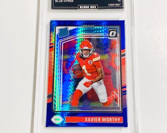 May include: A blue and red Xavier Worthy football trading card from the 2024 Donruss Optic series. The card is graded GEM MT 10 and features a photo of the player in action. The card is encased in a protective holder.
