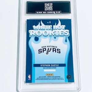 Może przedstawiać: Karta do koszyk&oacute;wki Stephon Castle San Antonio Spurs, oceniona z serii Panini Donruss Optic 2024-25. Karta jest zamknięta w przezroczystym plastikowym uchwycie przez Black Box Grading Club. Z tekstem "White Hot Rookies" i logo Spurs.