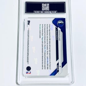 Puede incluir: Una tarjeta de baloncesto de Cooper Flagg calificada en un estuche protector transparente. La tarjeta presenta el logotipo de los Dallas Mavericks y la informaci&oacute;n del jugador. El estuche tiene una etiqueta negra con el texto "BLACK BOX GRADING CLUB".