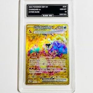 May include: A Charizard ex Hyper Rare Pokémon card, graded GEM MT 10, encased in a protective holder. The card features a gold background with a colorful illustration of Charizard. Text includes "2023 POKEMON OBF EN" and "Burning Darkness".