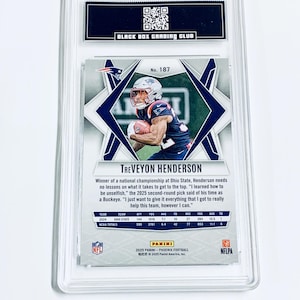 May include: A TreVeyon Henderson football card, graded by Black Box Grading Club. The card features a photo of the player in a Patriots uniform, with statistics and the Panini logo. The card is encased in a clear protective holder.
