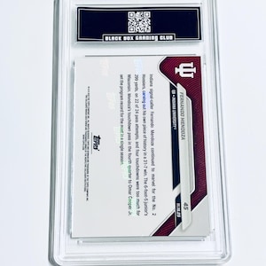 May include: A graded sports trading card encased in a clear plastic holder. The card features a maroon and white design with the name "FERNANDO MENDOZA" and "QB - INDIANA UNIVERSITY" printed on it. The card is from the Topps company.