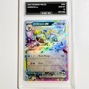 May include: A graded Umbreon ex Pokémon card. The card is encased in a clear plastic holder with a black label that reads "2025 POKEMON PRE EN UMBREON ex". The card features a colorful illustration of Umbreon.