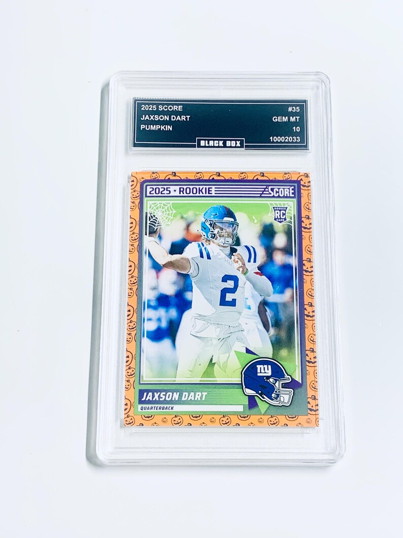 May include: A graded 2025 Score Jaxson Dart Pumpkin rookie football card. The card features a player in a blue and white uniform. The card is graded GEM MT 10 by Black Box. The card has a Halloween-themed border with pumpkins.