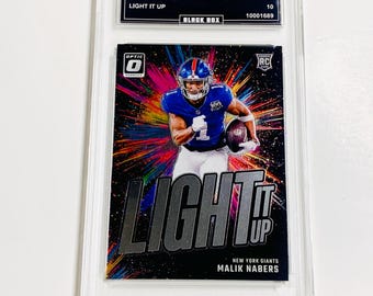 May include: A 2024 Donruss Optic trading card featuring Malik Nabers of the New York Giants. The card has a black background with the words "LIGHT IT UP" in large silver letters. The card is graded GEM MT 10.