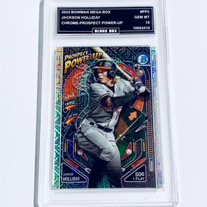 Könnte beinhalten: Eine weiße Keramik-Tasse mit schwarzem Henkel und dem Text "But First, Coffee" in fetter, schwarzer Schrift. Die Tasse steht vor einem verschwommenen Hintergrund, der eine gemütliche Umgebung suggeriert.