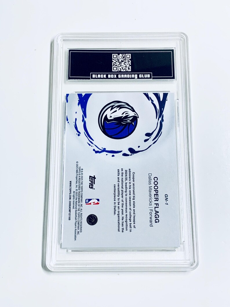 Puede incluir: Una tarjeta de baloncesto de Cooper Flagg de los Dallas Mavericks, calificada y protegida en una funda transparente. La tarjeta muestra el logotipo de los Mavericks y el texto "COOPER FLAGG" y "Dallas Mavericks | Forward". Calificada por Black Box Grading Club.