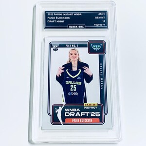 May include: A Panini Instant WNBA trading card featuring Paige Bueckers in a Dallas Wings jersey. The card is graded GEM MT 10 and encased in a protective holder. The card includes the text "DRAFT NIGHT" and "PICK NO. 1".