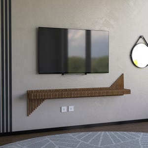 May include: A modern living room setup featuring a large, black flat-screen TV mounted above a wooden shelf. The shelf has a unique, slatted design. A round mirror hangs on the wall to the right. The room has a neutral color palette.