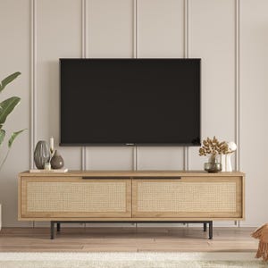 May include: A light wood TV stand with two woven cane doors and black metal legs. The stand is in front of a white wall with vertical panels. A black flat screen TV is mounted above the stand.