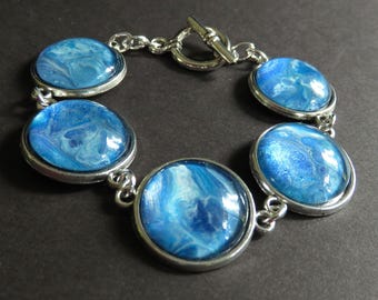 Pale blue fluid art cabochon bracelet. Wearable art. Fluid art bracelet. Flow art bracelet. Poured paint jewelry. Poured paint bracelet.