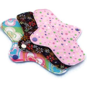 May include: Three reusable cloth menstrual pads in different patterns. The top pad is pink with white and purple polka dots. The middle pad is black with a floral pattern. The bottom pad is multi-colored with a heart pattern.