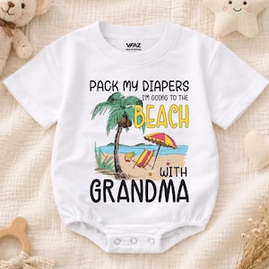 May include: A white short-sleeved baby bodysuit featuring a graphic of a palm tree, a beach chair, and an umbrella with the text "PACK MY DIAPERS I'M GOING TO THE BEACH WITH GRANDMA" printed in black and yellow lettering on the front center.