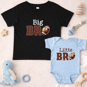 May include: Black t-shirt with "Big BRO" text and a football graphic. A light blue onesie with "Lilttle BRO" text and a football graphic. Baby and toddler apparel.