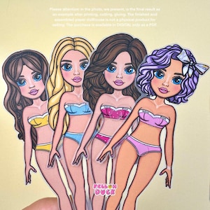 May include: Four paper doll cutouts with different hairstyles and swimwear. The dolls have blue eyes, pink lips, and wear bikinis in yellow, light blue, pink, and purple. The text "YELLOW DUCK" is visible on the bottom right.