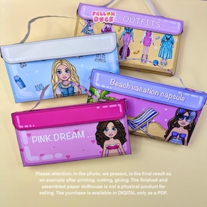 May include: Four colorful paper dollhouse kits with illustrations of dolls and outfits. The kits are labeled "PINK DREAM", "YELLOW DUCK OUTFITS", and "Beach vacation capsule". Each kit features a different theme and design.