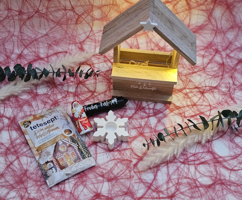 May include: A white snowflake candle holder, a small red and white Santa Claus figurine, a brown paper packet with the text "tetesept. Dein s&uuml;&szlig;er Wintertraum" and a black and white candle with the text "Fr&ouml;hliches Fest!" on a red and white background.