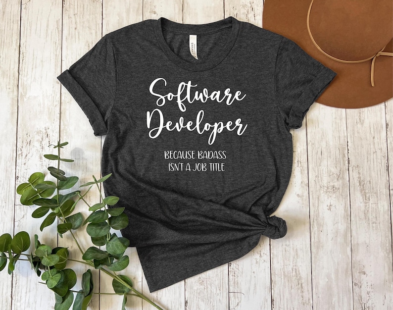 May include: A dark gray t-shirt with the text "Software Developer Because Badass Isn't A Job Title" printed in white.