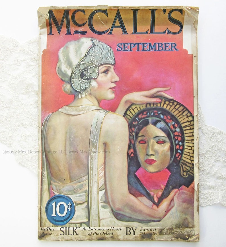May include: A vintage McCall's magazine cover from September, featuring a woman in a white dress and a beaded headband, holding a mask with a woman's face. The cover text reads "McCall's" and "September" and includes the price "10&cent;".