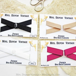 May include: Four cards with white backgrounds and black text. Each card features a different color French bra back closure. The colors are black, beige, white, and pink.