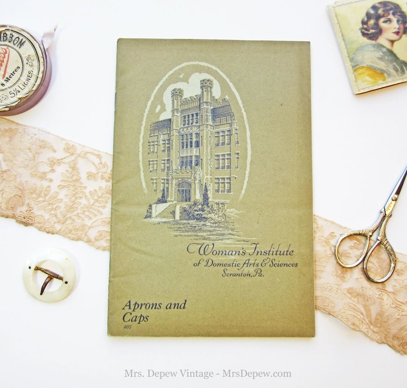Puede incluir: Un folleto verde vintage con una ilustraci&oacute;n en blanco y negro de un edificio. El folleto se titula "Woman's Institute of Domestic Arts & Sciences Scranton, Pa." y "Aprons and Caps 405".