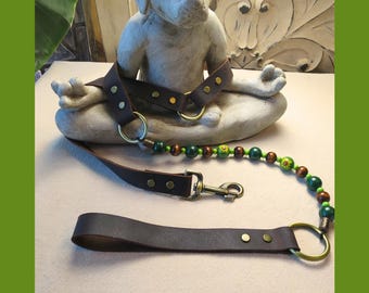 May include: A brown leather pet harness and leash set. The harness features brass-colored rings and hardware. The leash includes a beaded section with green, brown, and yellow beads. The set is designed for small pets.